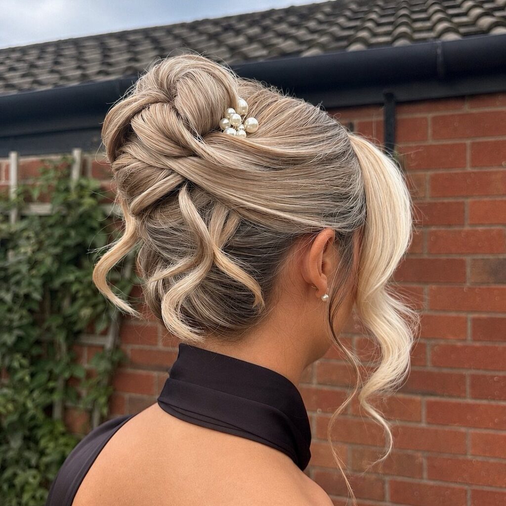 Woman showing an elegant blonde braided updo with curls and pearl hair accessory