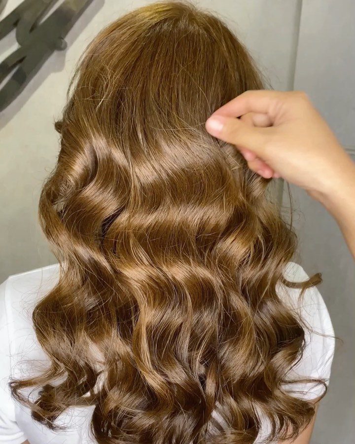 Long brown hair with golden highlights styled in glossy curls