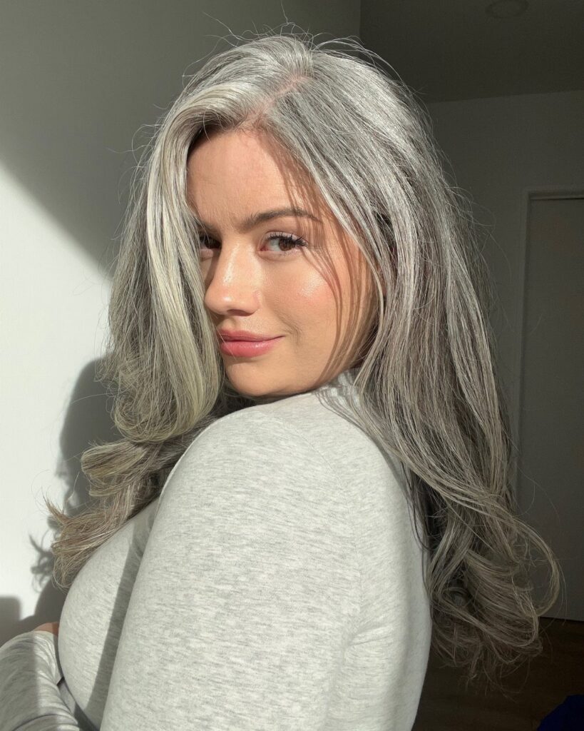 Woman with long, wavy silver-gray hair looking over her shoulder