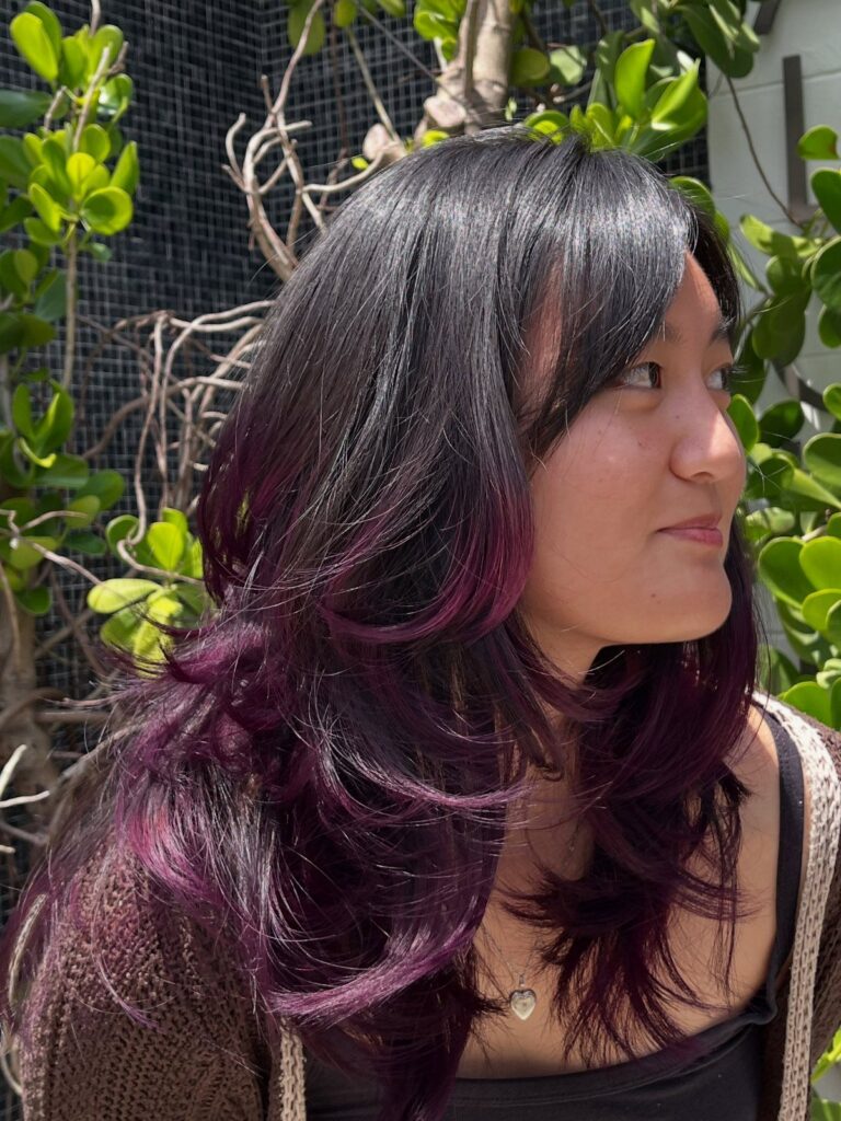 Woman showing long dark hair with purple-tinted layered ends