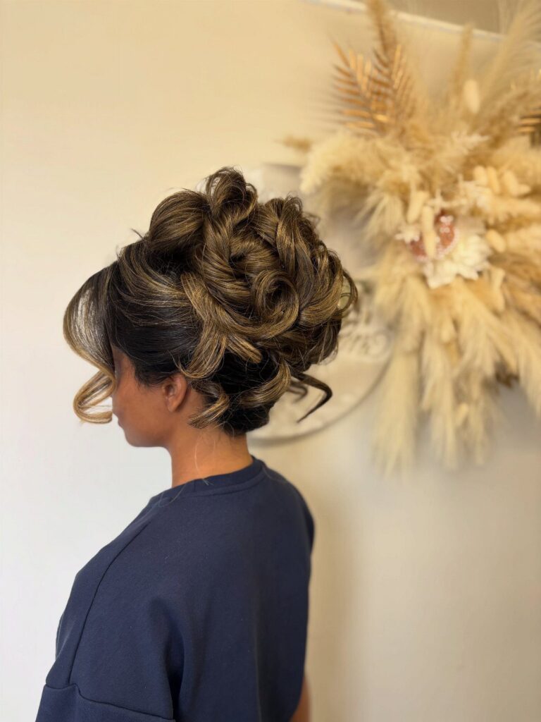Woman with an elaborate braided updo and loose curls, viewed in profile