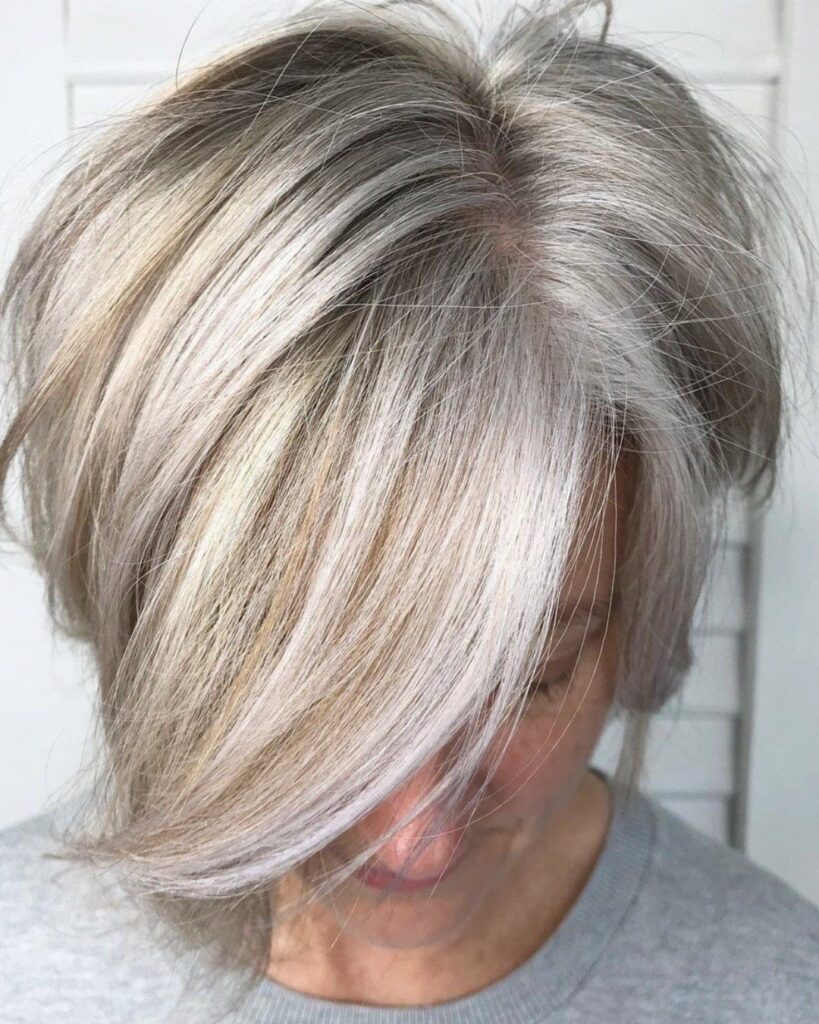Layered silver-gray hair swept across the face with blonde highlights
