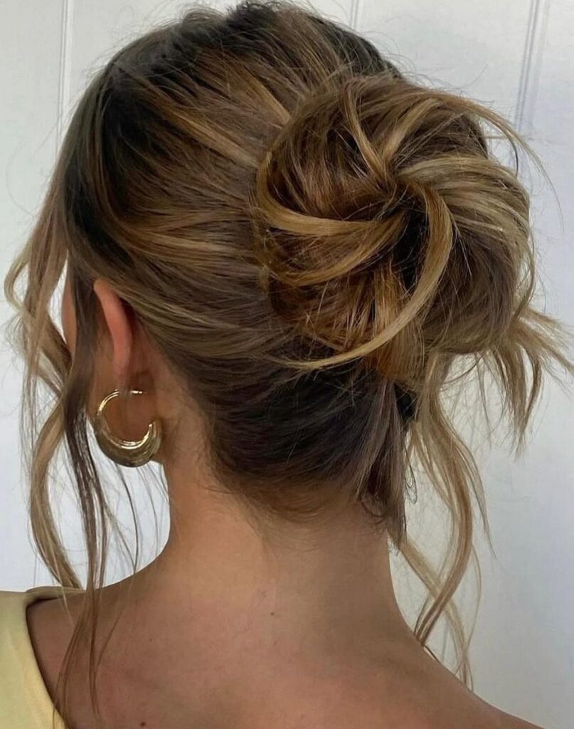 Loose brown updo with pinned twists and wispy strands, viewed from behind