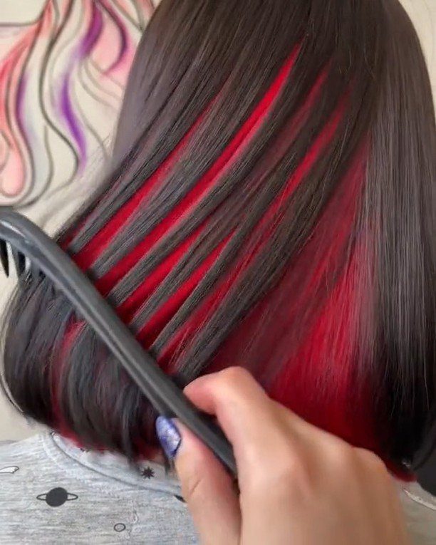 Dark hair with bright red peekaboo sections separated by a comb