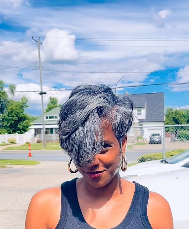 Woman showcasing a short layered gray hairstyle with side-swept fringe outdoors